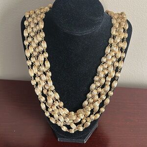 Vintage Monet 6 strand etched gold bead necklace. Signed on the clasp.